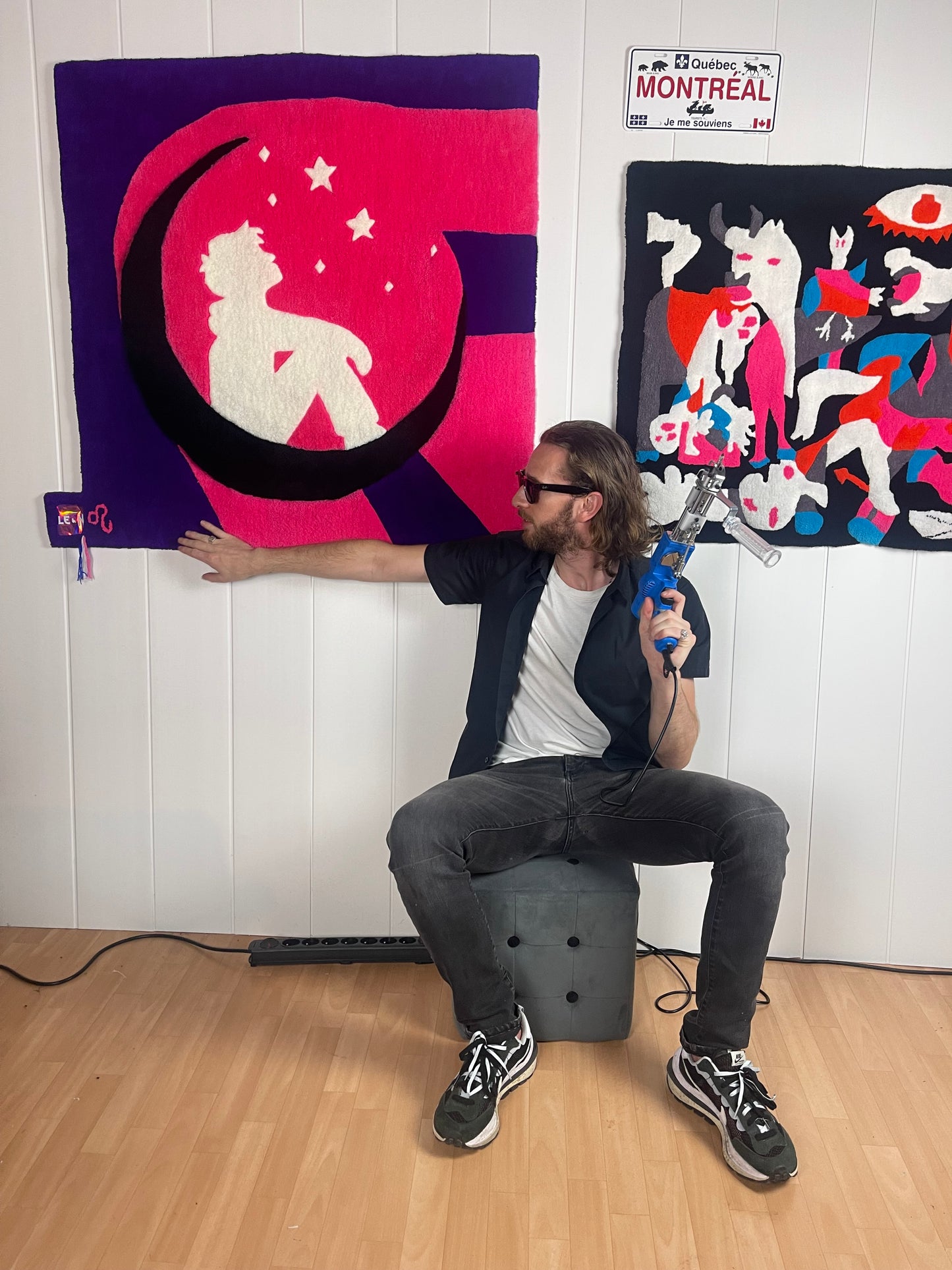 Artisan créateur Signé Léon présentant son grand tapis mural original Léon avec un pistolet à tufter dans son atelier.