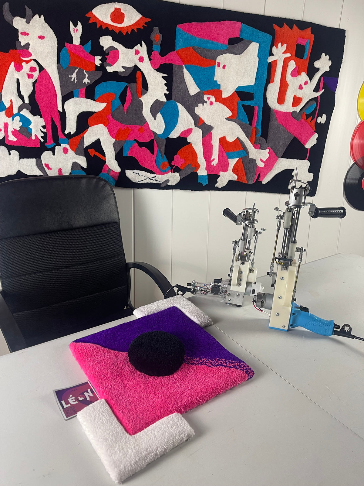 Matériel de l'atelier Masterclass Signé Léon : un échantillon de tapis tufté avec un effet de relief 3D posé sur une table à côté de deux tufting guns, dont une machine spécifique "long pile" pour créer du volume.