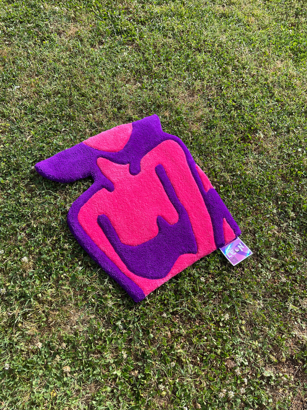 Vue de biais de la création textile Alien Girl sur l'herbe, mettant en valeur les courbes stylisées du buste féminin et l'épaisseur du tufting.