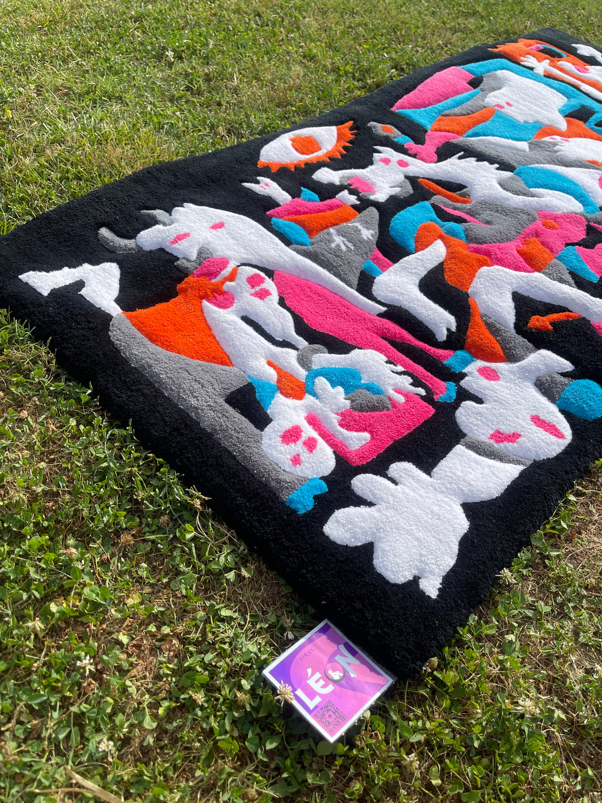 Gros plan sur les couleurs vives du tapis tufté Guernica avec l'étiquette de la marque artisanale Signé Léon.