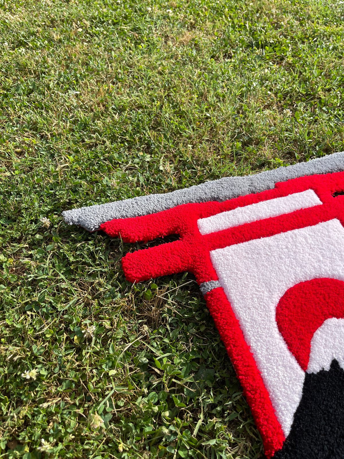 Gros plan sur la structure gauche du portique Torii rouge et gris, minutieusement tufté à la main sur la création d'inspiration nippone.