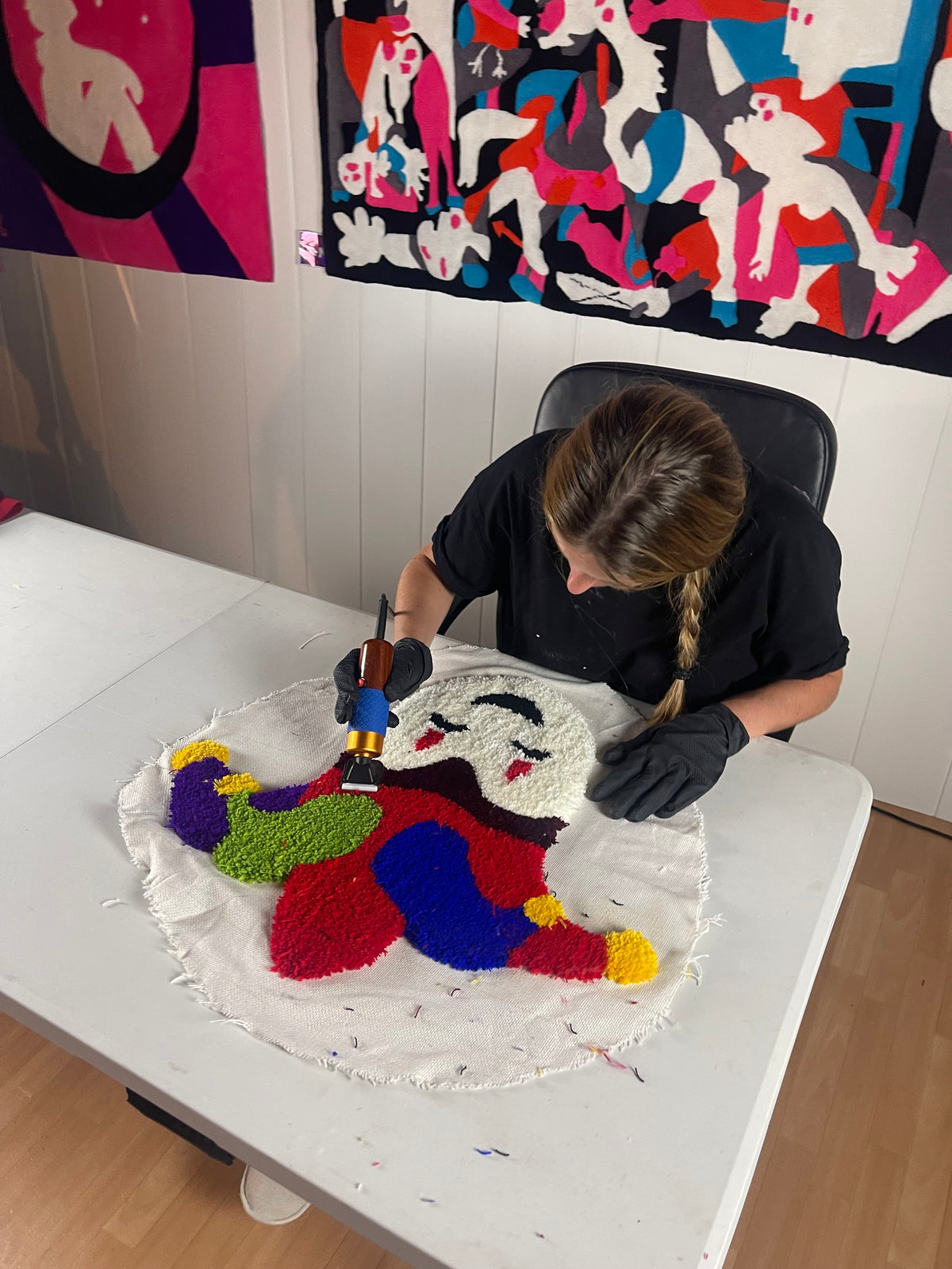 Une participante concentrée réalisant les finitions et la tonte de son tapis coloré à l'aide d'une tondeuse lors de son stage d'initiation au tufting dans l'atelier Signé Léon à Toulouse.