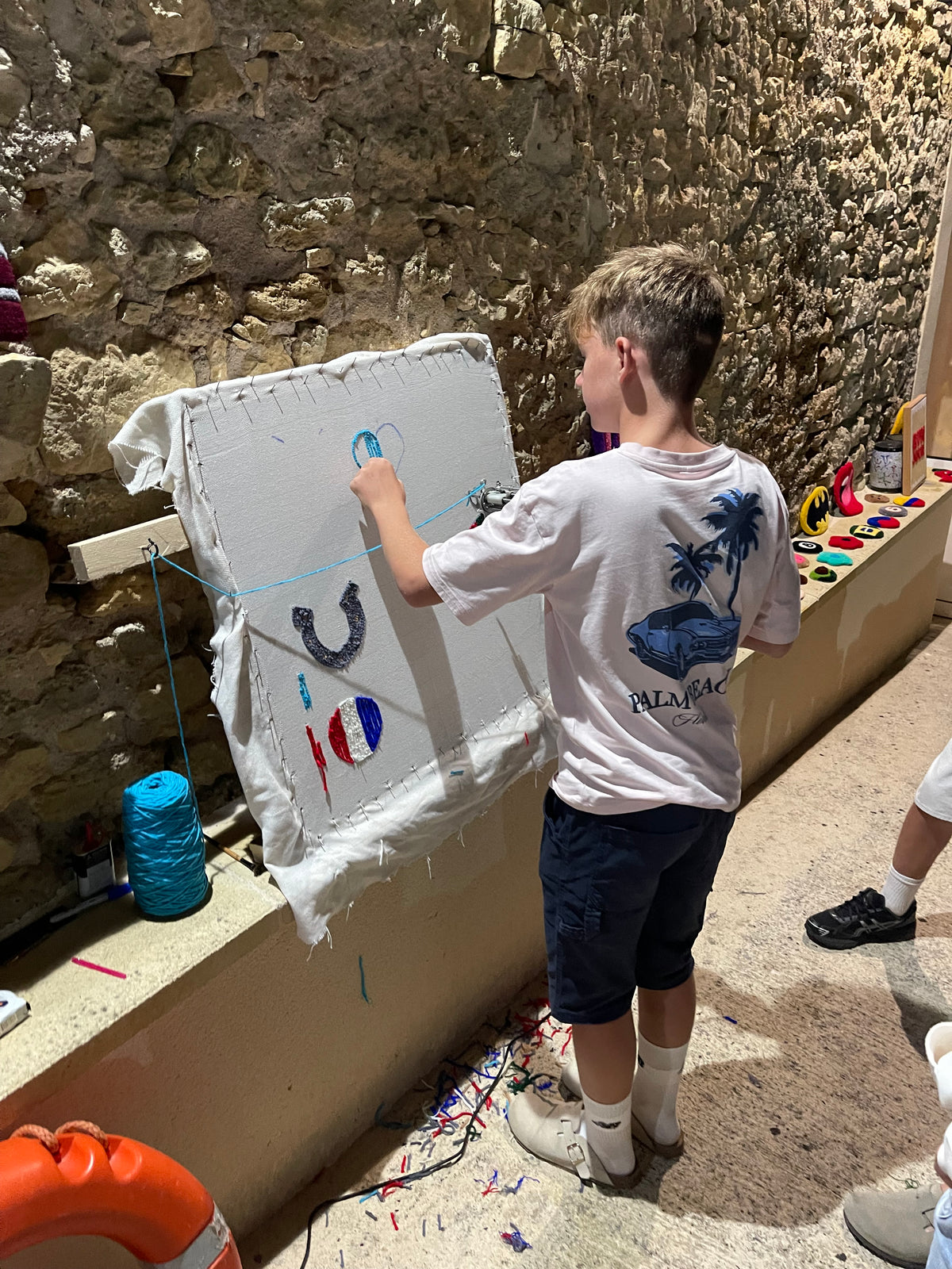 Jeune garçon apprenant à utiliser un tufting gun dans son jardin lors d'un atelier découverte du tufting à domicile.