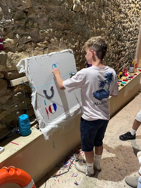 Jeune garçon apprenant à utiliser un tufting gun dans son jardin lors d'un atelier découverte du tufting à domicile.