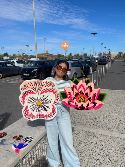 Cliente ravie tenant ses deux tapis tuftés sur mesure en forme de fleurs après les finitions (tonte et carving) réalisées par l'artisan Signé Léon.
