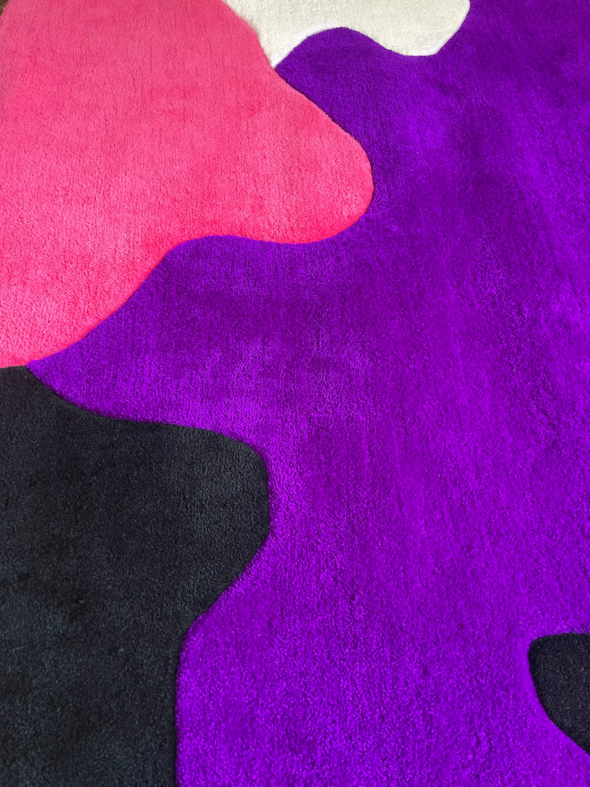 Macro sur la douceur et la densité des fils acryliques roses, violets et noirs utilisés pour le tufting de l'œuvre.