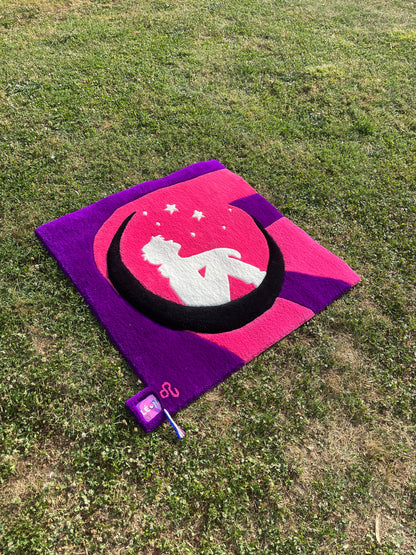 Œuvre décorative murale textile au design pop posée sur l'herbe, mettant en valeur ses proportions harmonieuses de 100x100 cm.
