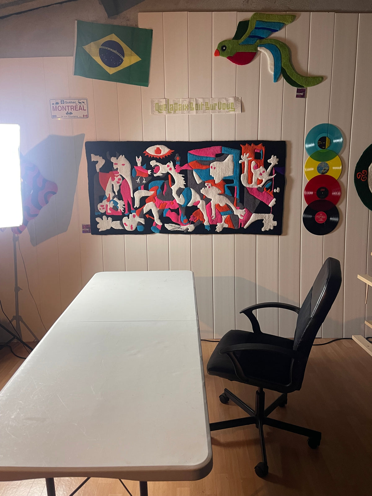 Mise en situation de l'œuvre textile Guernica Colorée sur le mur de l'atelier toulousain Signé Léon, avec éclairage photo.