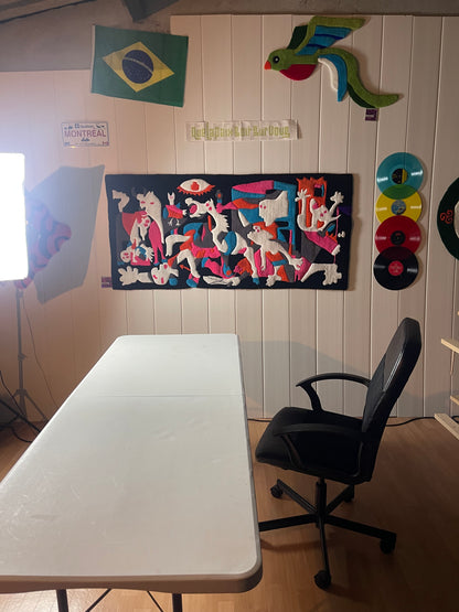 Mise en situation de l'œuvre textile Guernica Colorée sur le mur de l'atelier toulousain Signé Léon, avec éclairage photo.