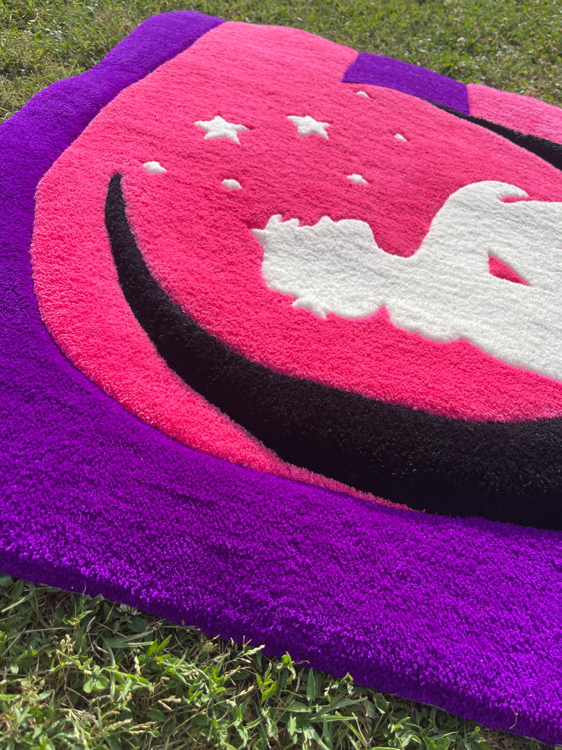 Gros plan sur la silhouette blanche inspirée du Petit Prince et les étoiles tuftées sur fond rose fuchsia.