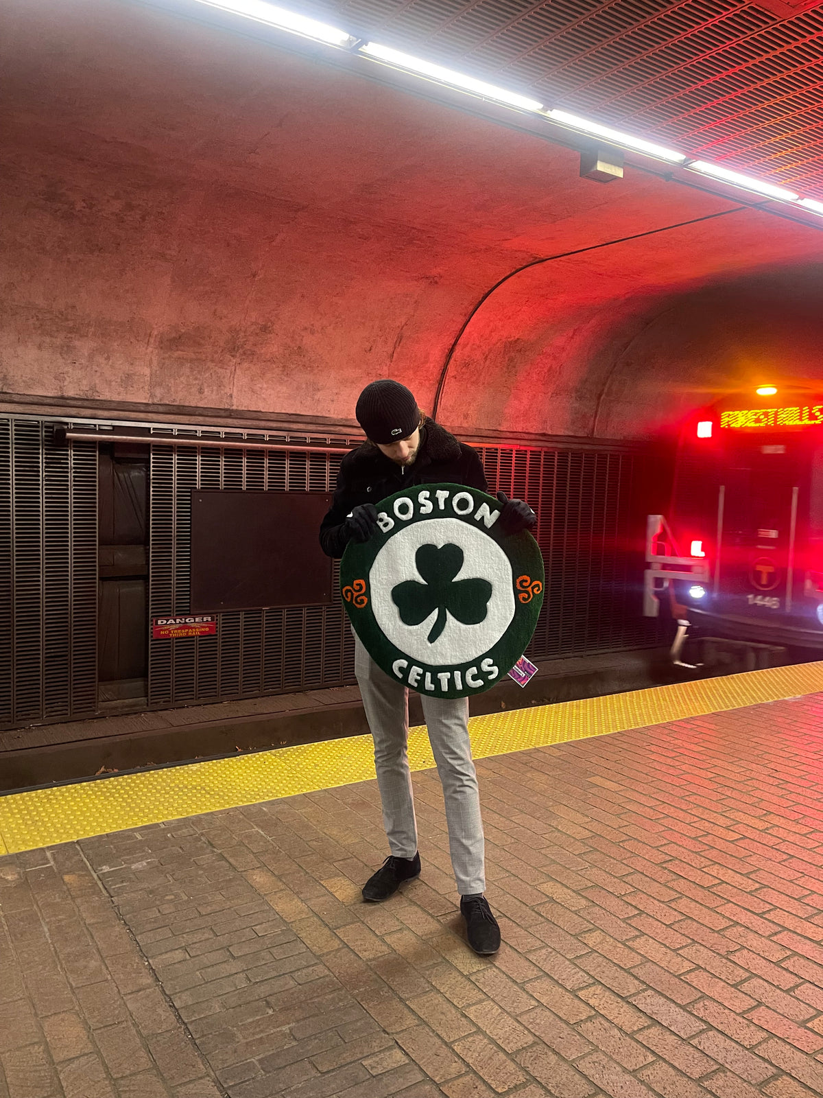 L'artisan Signé Léon présentant son tapis tufté du logo des Boston Celtics dans une station de métro souterraine dans la ville de Boston.