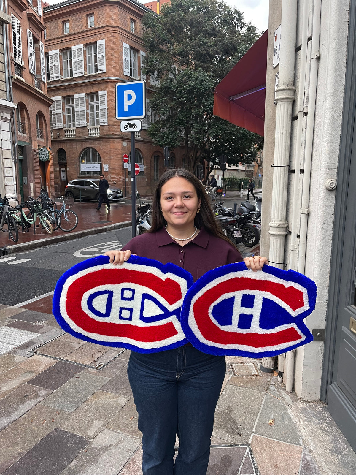 Participante posant dans les rues de Toulouse avec son grand tapis logo réalisé sur mesure pendant l'atelier.