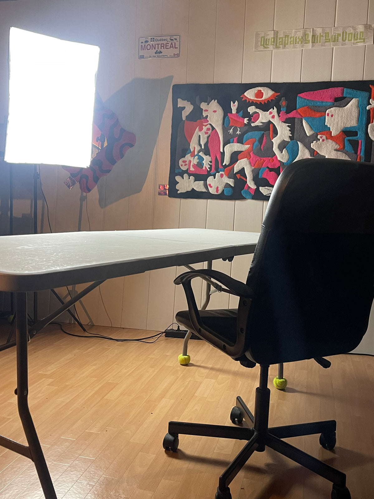 La grande tapisserie tuftée Guernica Colorée accrochée au mur dans l'atelier de création Signé Léon à côté d'un bureau.