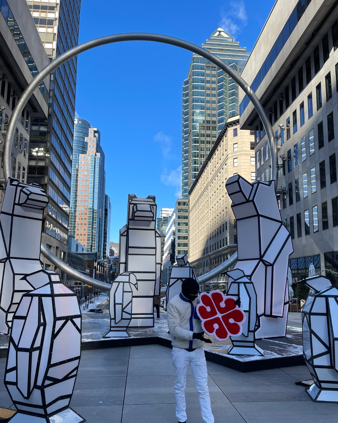 L'artisan Signé Léon présentant sa création sur mesure, un tapis tufté reprenant le logo rouge de Montréal, mis en scène en plein centre-ville sous la célèbre structure de l'Anneau à la Place Ville Marie, au milieu de sculptures hivernales.
